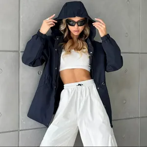Trendy model wearing navy blue waterproof hooded windbreaker with white sporty pants
