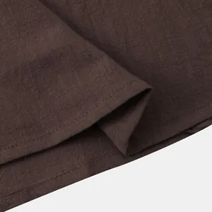 Close-up macro detail of premium brown cotton linen fabric and stitching on men's shirt.