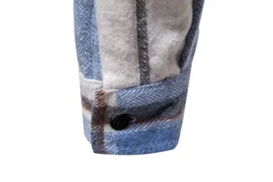 Primer plano detallado del puño de una camisa de cuadros azul con botón y franela.