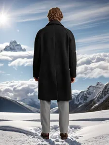 Back view of a men's long dark woolen coat in a majestic snowy mountain landscape.