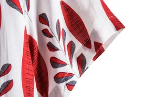 Macro detail of men's summer shirt with red and grey leaf pattern and fine stitching.
