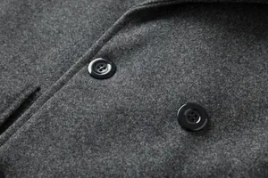 Detailaufnahme eines grauen Wollmantels mit hochwertiger Textur und schwarzen Knöpfen