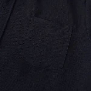 Detail of chest pocket and waffle texture on men's navy blue casual short-sleeved shirt