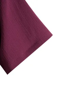 Macro view showing the crinkle fabric texture on a deep purple men's short sleeve shirt