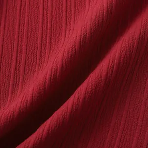 Primer plano de tela roja texturizada con patrón de pliegues verticales y material suave