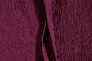 Macro detail of dark purple crinkle fabric texture on men's short sleeve shirt