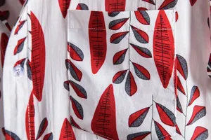 Macro detail showing red leaf pattern print and pocket stitching on a white men's shirt.