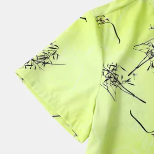 Gros plan d'une manche de chemise hawaïenne jaune néon avec motif floral sombre.