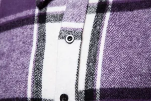Detalle macro de la tela de camisa de franela a cuadros morados con botón negro