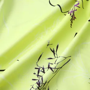 Vue rapprochée du tissu hawaïen vert citron avec motifs de feuilles et texture légère.