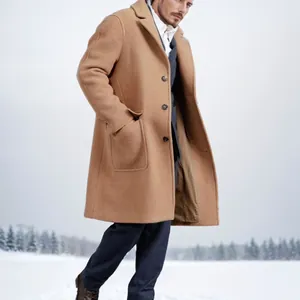 Elegant men's camel long wool overcoat featuring single-breasted buttons in snow landscape.