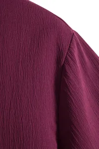 Close-up macro detail showing the textured creped fabric on a purple men's short-sleeve shirt