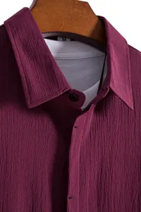 Macro close-up view showing the textured burgundy crinkle fabric of a men's casual shirt collar