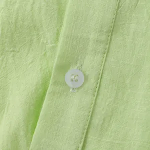 Close-up detail of the lime green cotton linen shirt showing fabric texture and button