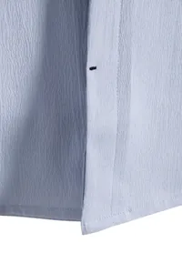 Detailed macro view showing the textured light blue fabric and precise stitching of a men's shirt