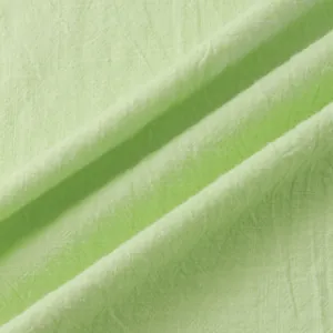 Macro detail showing the breathable light green cotton linen fabric texture of a summer shirt