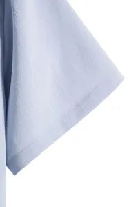Close-up macro view of a light blue men's short sleeve shirt showing premium fabric texture.