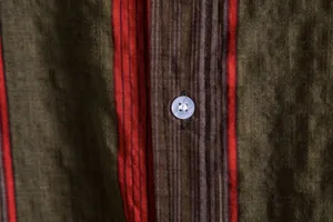 Close-up of striped textured fabric and button detail on a men's casual summer shirt.