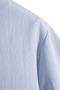Close-up detail of light blue textured fabric and seam on men's short sleeve shirt