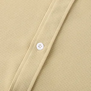 Close-up of beige waffle texture fabric and white button on men's casual shirt