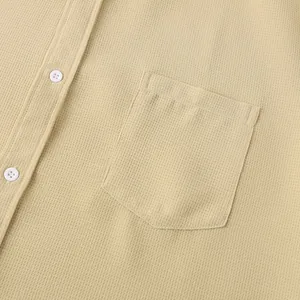Macro detail of beige waffle knit men's casual shirt with chest pocket and white buttons