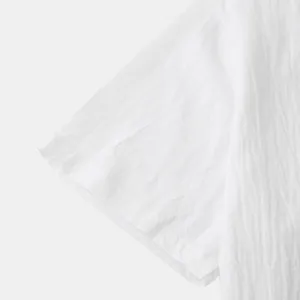 Detail view of white cotton linen shirt sleeve showing its natural fabric texture