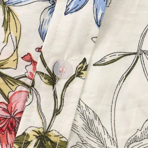 Dettaglio ravvicinato della trama del tessuto a fiori e del bottone di una camicia estiva