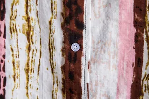 Close-up detail showing the button, stitching, and fabric texture of a floral casual shirt.