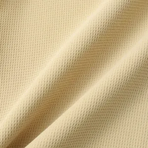 Detailed macro shot of beige waffle knit fabric texture for a men's casual summer shirt.