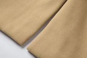 Detailaufnahme der weichen Textur und sauberen Nähte des kamelfarbenen Wollmantels.