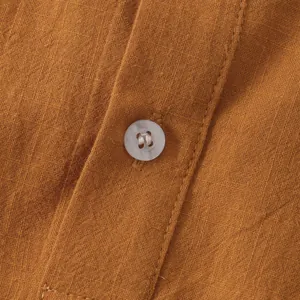 Macro detail showing the white button and premium linen texture of an orange summer shirt