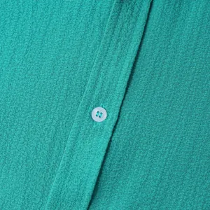 Macro detail of teal men's shirt showing breathable crinkle fabric texture and button detail