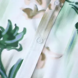 Vue rapprochée de l'imprimé floral vert et des boutons d'une chemise hawaïenne pour hommes