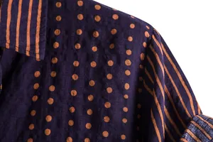 Detail view of men's casual shirt with orange polka dots and striped pattern on blue