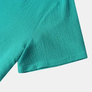 Close-up detail of teal men's short sleeve shirt showing breathable crepe fabric texture