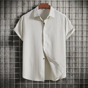 Macro view of cream-colored textured short-sleeved button-up shirt hanging on wooden hanger.