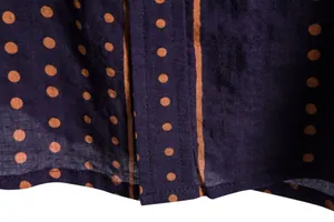 Detailed macro view of dark blue floral shirt fabric featuring orange polka dots and stripes texture