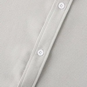 Detail shot of grey waffle knit fabric and white buttons on a men's casual shirt