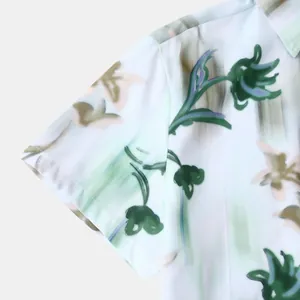 Détail d'une chemise hawaïenne pour homme avec un imprimé floral vert sur la manche courte.