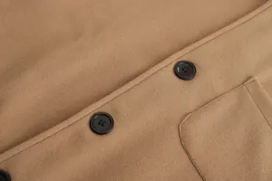 Nahaufnahme eines khakifarbenen Wollmantels mit schwarzen Knöpfen und Stoffstruktur