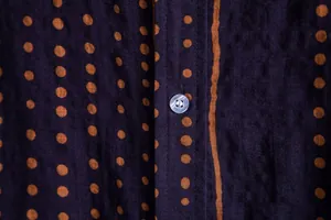 Macro view of men's casual shirt fabric with orange polka dots and button detail