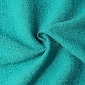 Macro view of teal textured fabric showing the fine crinkled weave and soft drape