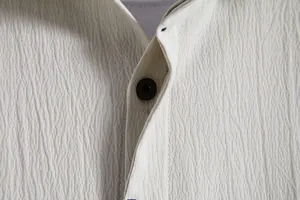 Close-up detail of textured fabric and button on men's beige short-sleeve shirt