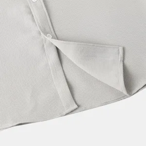 Macro detail of men's grey waffle knit casual shirt showing fabric texture and hem.