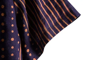 Close-up detail of men's shirt sleeve with orange stripes and polka dots pattern