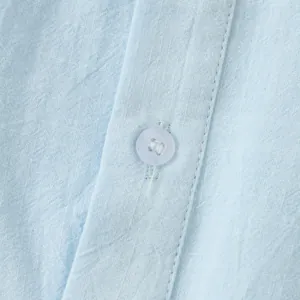 Close-up detail of light blue breathable linen cotton shirt fabric texture and button