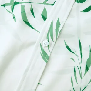 Gros plan montrant le motif de feuilles vertes et le bouton blanc d'une chemise hawaïenne