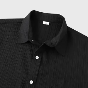 Primer plano detallado del tejido negro texturizado y el cuello de una camisa de hombre de manga corta