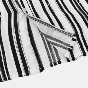 Close-up of hem and button detail on black and white striped casual shirt.