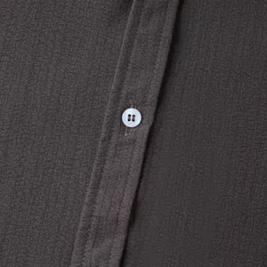 Macro detail of dark grey short sleeve shirt fabric texture with a white button